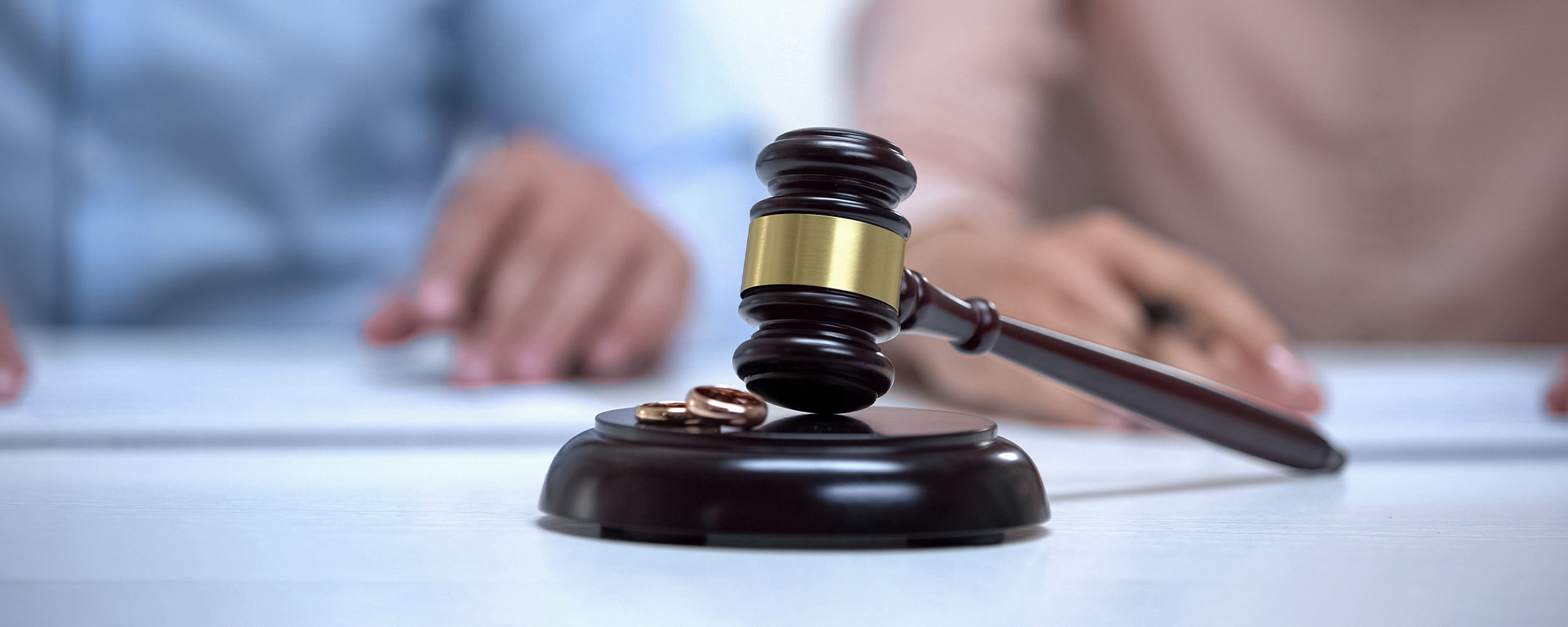 Judges gavel on a desk with a couple considering divorce; Business Owner Divorce Attorneys concept image