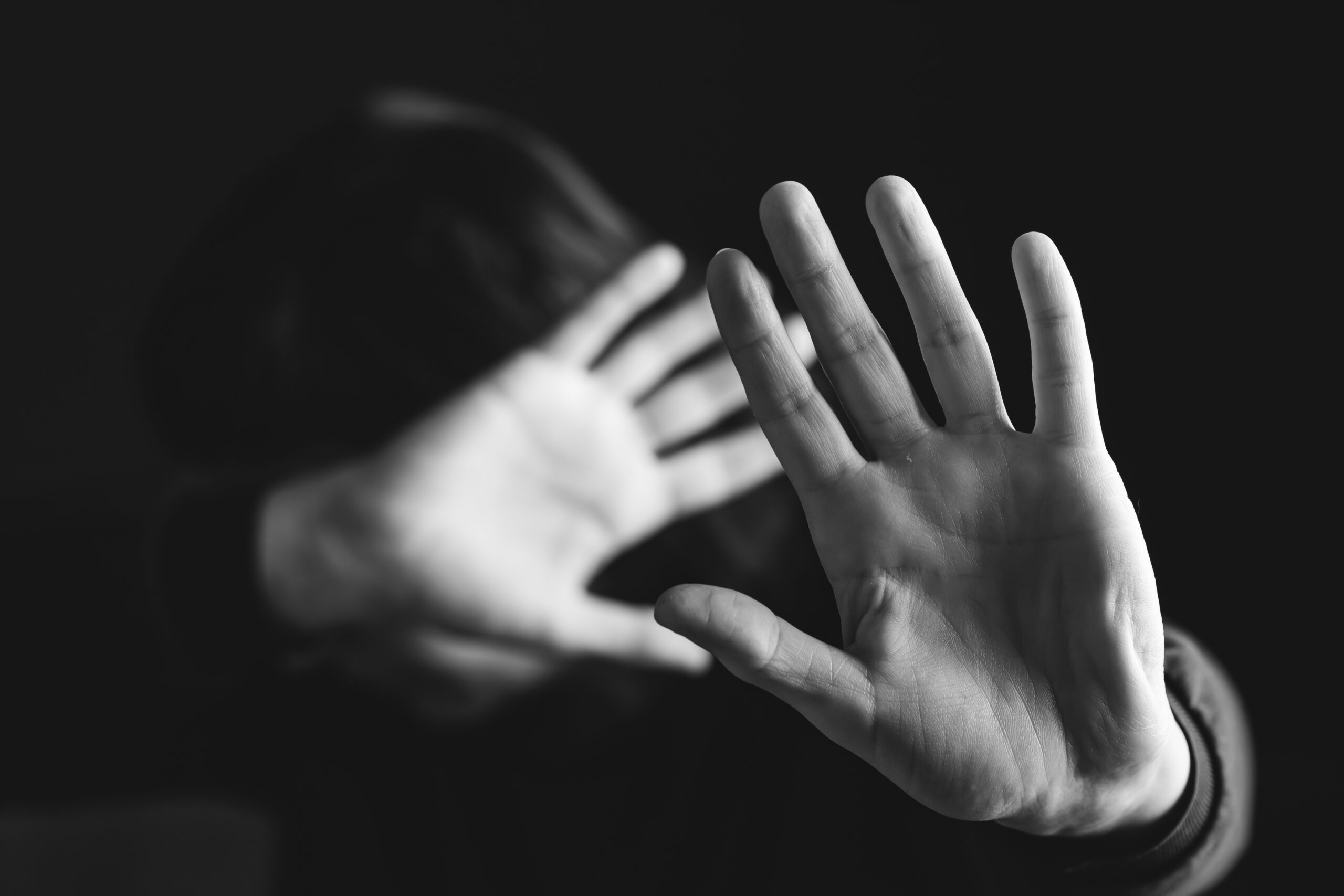 person with hands up protecting their face