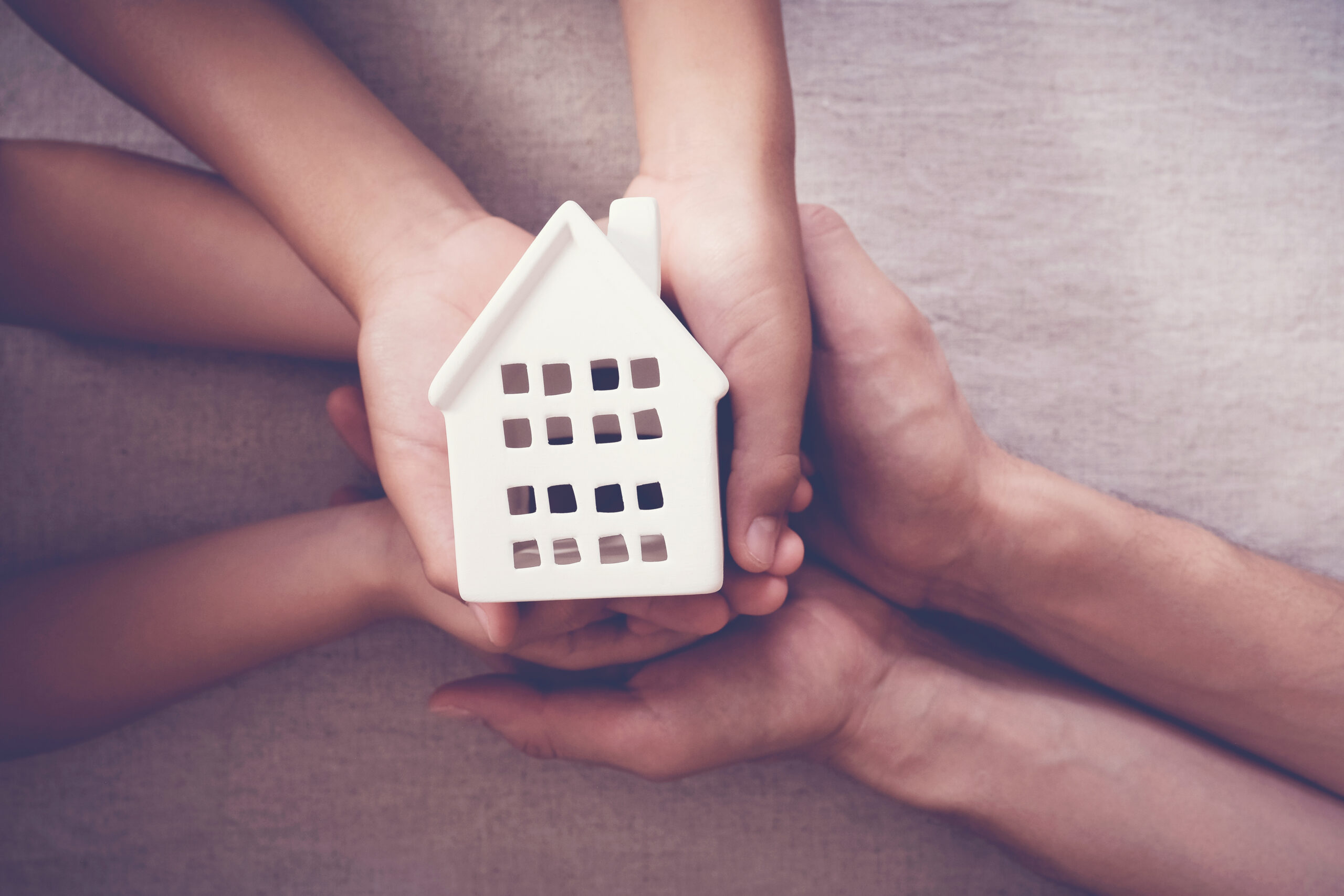 Adult and child hands holding white house, family home