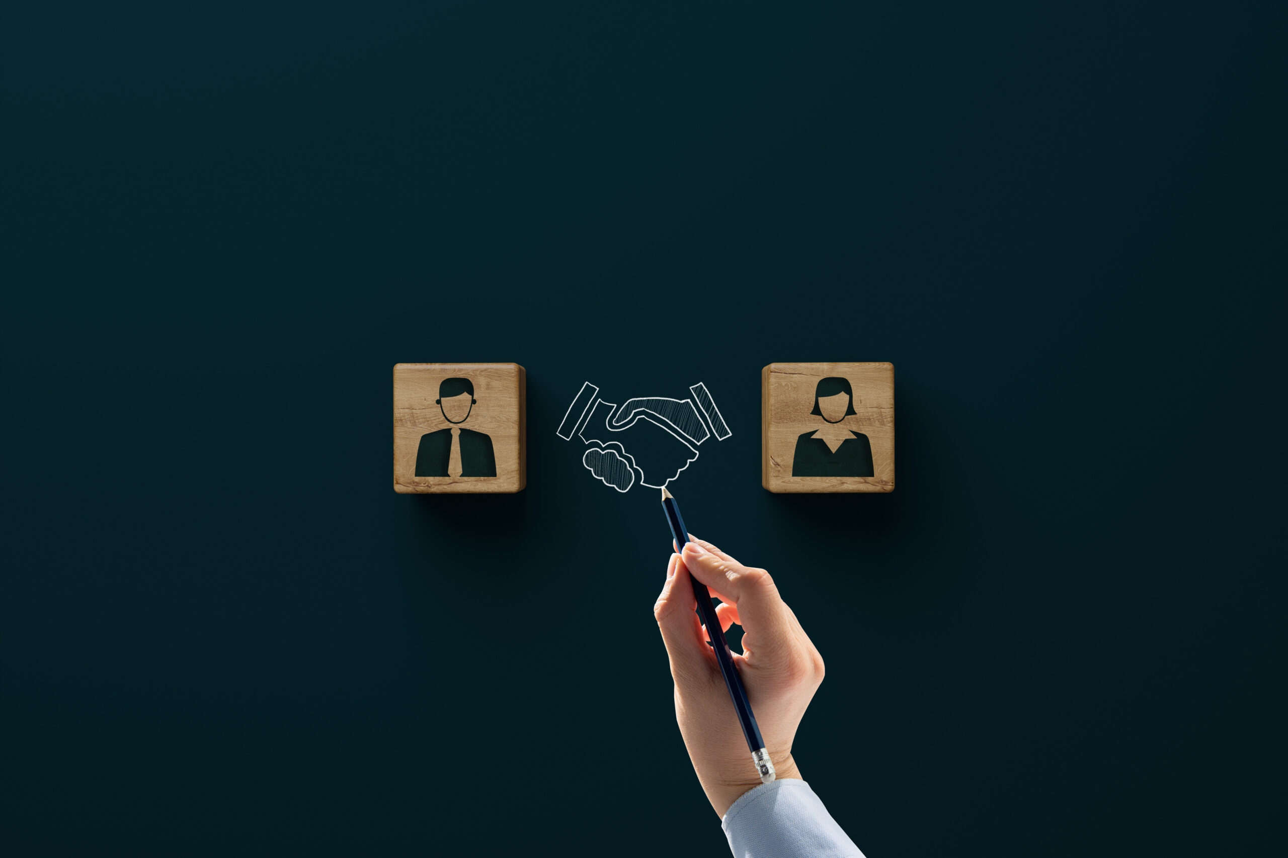 Wooden blocks with an icon of a man, woman and shaking hands with consent. Divorce, mediation concept. Troubleshooting by a mediator.